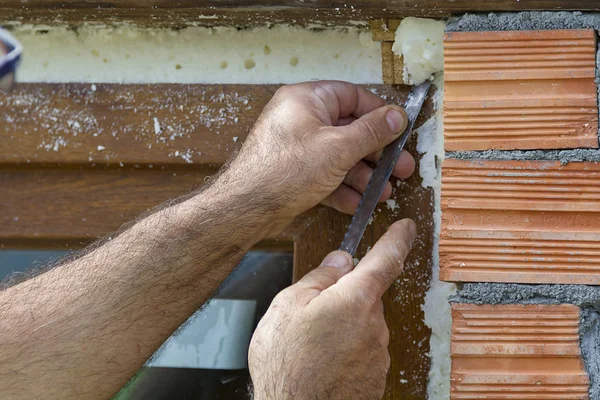 A man building a brick wall and a window