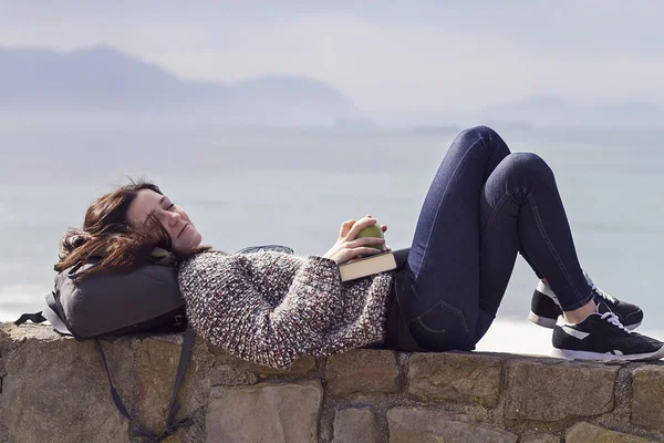 A girl having rest and reading by the sea