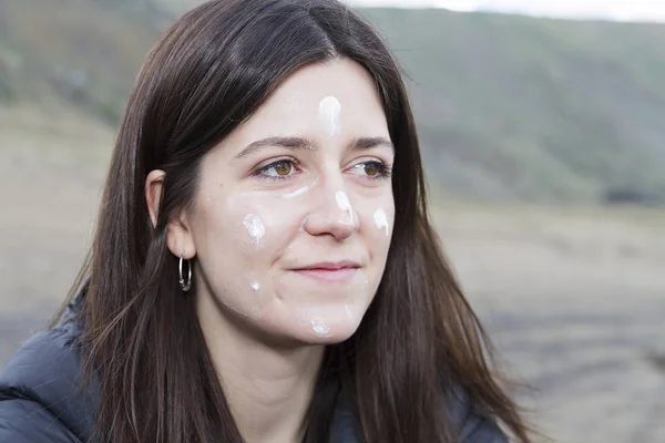 A young woman spreading sun cream over her face