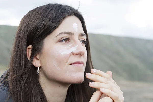 A young woman spreading sun cream over her face