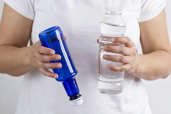 A woman holding bottles of plastic or glass