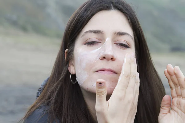 Uma Jovem Mulher Espalhando Protetor Solar Sobre Rosto — Fotografia de Stock