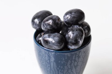 Mavi bir fincan büyük siyah üzüm bir demet