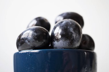 Mavi bir fincan büyük siyah üzüm bir demet