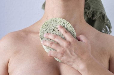 Vücudunu süngerle yıkayan bir kadın.