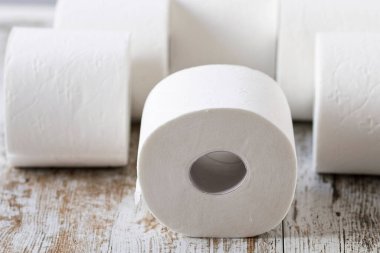 Ahşap arka planda yuvarlanan yumuşak tuvalet kağıdı yığını.