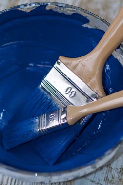 İki fırça ve bir kase ile koyu mavi tebeşir boyası