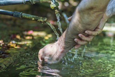 Bir günlük saha çalışmasından sonra ellerini çamurdan temizleyen bir adam.