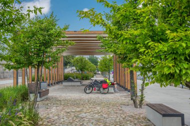 Modern şehir, bir geçit üzerinde bir bankta oturan bisikletçi