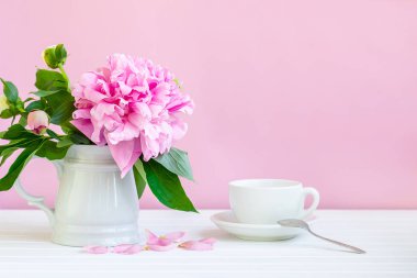 Bir fincan çay ve bir vazoda peonies