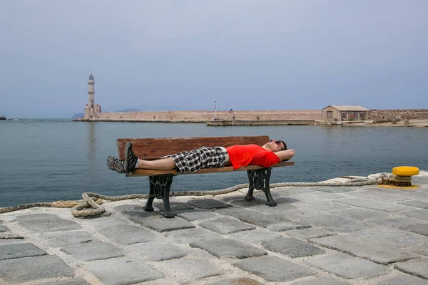 Mujer joven sentada en el banco y mirando el puerto viejo en Chania, Grecia — Foto de Stock