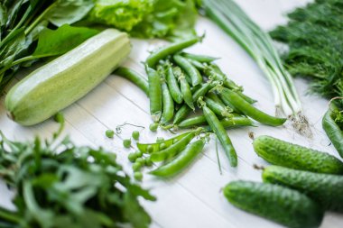 Beyaz bir arka plan üzerinde bileşimi yeşil organik vejetaryen Ürünler: yeşil yapraklı sebzeler, fasulye, kabak, sarımsak, soğan, salatalık, biber, ıspanak. Yukarıdan görüntüleyin. Yeşil yiyecek