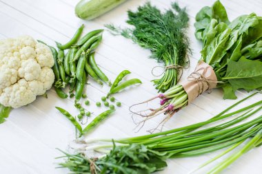 Beyaz bir arka plan üzerinde bileşimi yeşil organik vejetaryen Ürünler: yeşil yapraklı sebzeler, fasulye, kabak, sarımsak, soğan, salatalık, biber, ıspanak. Yukarıdan görüntüleyin. Yeşil yiyecek