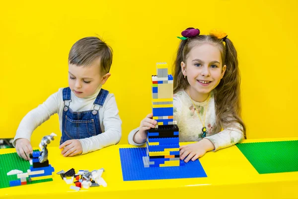 Lego, sarı bir arka plan üzerinde oynarken kardeşler.