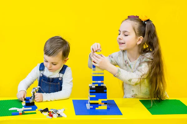 Lego, sarı bir arka plan üzerinde oynarken kardeşler.