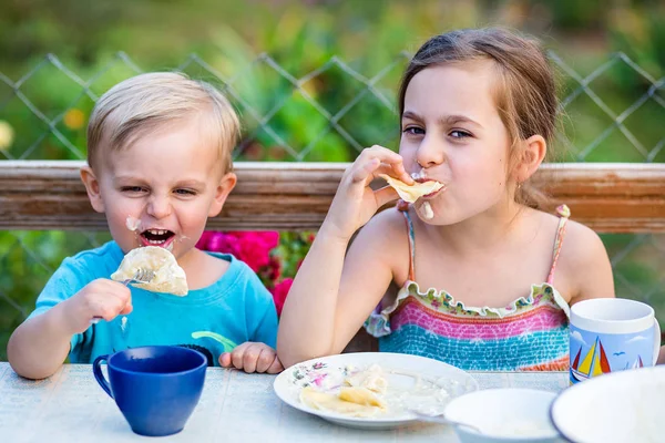 Funny boy and girl eating dumplings and making a mess