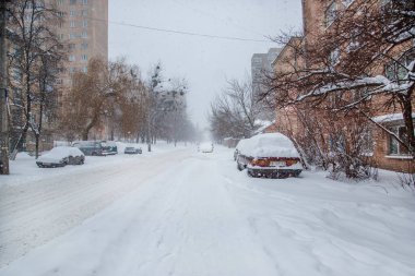 Araç park yerinde bir kış kar fırtınası kar kaplı. Karla kaplı yollar ve şehrin sokaklarında.