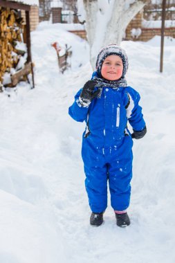 Bir çocuk ve bir sıcak kış takım elbise eldiven, bir kış günü açık havada üzerinde oynama ile portre. Kardan adam kör, kartopu çocuk eğlenceli oyun.
