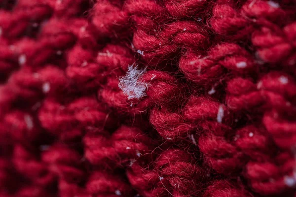 Kırmızı bir closeup ekose üzerine kaç kar taneleri ile ördü. Makro çekim.