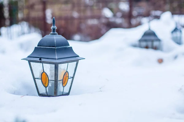 Garden lantern in the winter garden in the middle of the snow. Snowdrifts of snow in the garden.