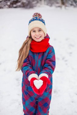 Bir kız kırmızı eldiven bir kalp şeklinde kartopu tutar. Sevgililer günü için aşk sembolü.