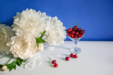 Bir buket peonies seramik vazo, çay ve tablo, mavi zemin üzerine çilek. Bahar sabahı, romantik ruh hali.