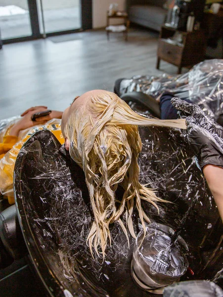 Cabeleireiro lavar o cabelo para uma menina loira . — Fotografia de Stock