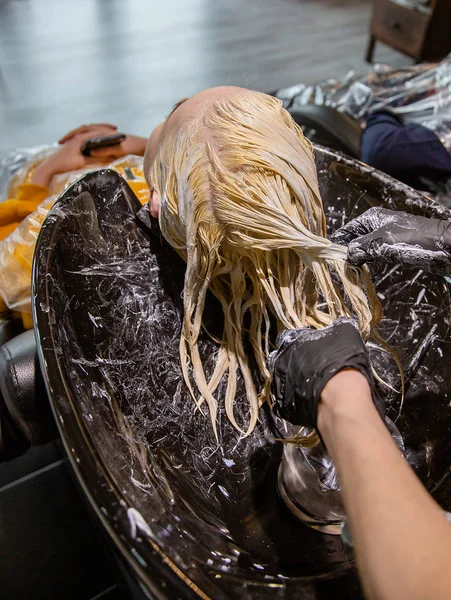 Cabeleireiro lavar o cabelo para uma menina loira . — Fotografia de Stock