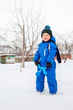 Mutlu çocuk heykel yapar ve kartopu atar. Temiz havada kış oyunları.