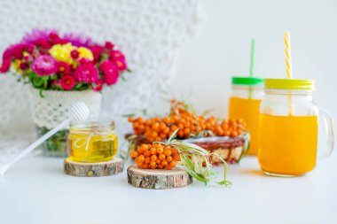 Beyaz arka plan, doğal ışıklandırma. Deniz dikeni meyveleri, kekik ve bal ile sıcak tatlı organik çay.