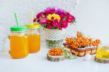 Beyaz arka plan, doğal ışıklandırma. Deniz dikeni meyveleri, kekik ve bal ile sıcak tatlı organik çay.