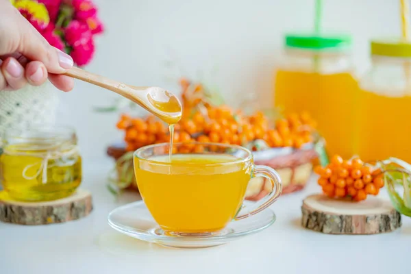 White background, natural lighting. Warm sweet organic tea with sea buckthorn berries, thyme and honey. — Stock Photo, Image