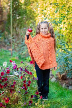 Güneşli bir sonbahar gününde bahçede elinde bir elma ile Sevimli mutlu kız.