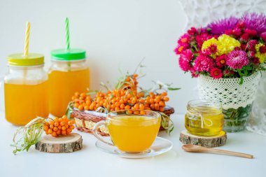 Beyaz arka plan, doğal ışıklandırma. Deniz dikeni meyveleri, kekik ve bal ile sıcak tatlı organik çay.