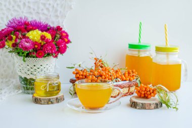 Beyaz arka plan, doğal ışıklandırma. Deniz dikeni meyveleri, kekik ve bal ile sıcak tatlı organik çay.