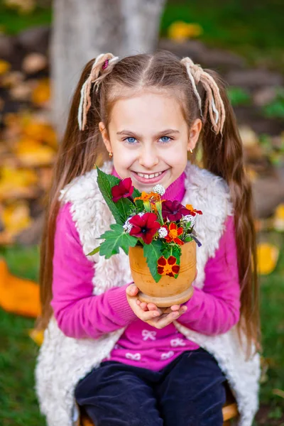 Cute happy girl with autumn bouquet of flowers in the garden on a sunny autumn day. — Stock Photo, Image