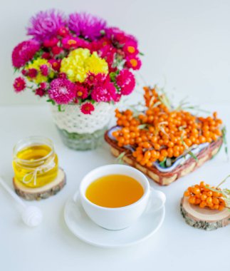 Beyaz arka plan, doğal ışıklandırma. Deniz dikeni meyveleri, kekik ve bal ile sıcak tatlı organik çay.