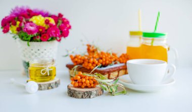 Beyaz arka plan, doğal ışıklandırma. Deniz dikeni meyveleri, kekik ve bal ile sıcak tatlı organik çay.