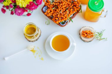 Beyaz arka plan, doğal ışıklandırma. Deniz dikeni meyveleri, kekik ve bal ile sıcak tatlı organik çay.