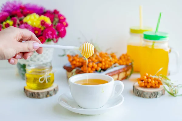 White background, natural lighting. Warm sweet organic tea with sea buckthorn berries, thyme and honey. — Stock Photo, Image