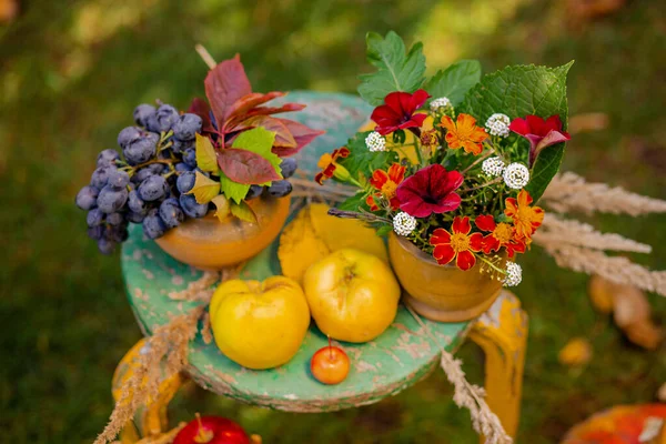 Autumn composition with grapes, quince and flowers located in the garden on a blurred green natural background. Royalty Free Stock Images