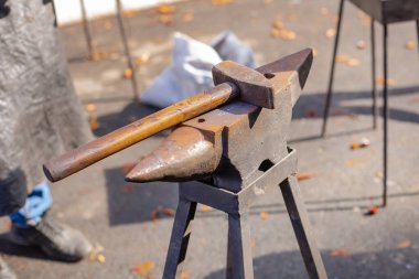 Bir demirci, seyircilerin önünde örsün üzerinde metal dövmesi yapar..