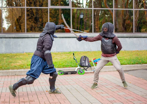 Dos hombres armados lideran una lucha con espadas, una lucha medieval, en un divertido torneo medieval. Competiciones deportivas . —  Fotos de Stock