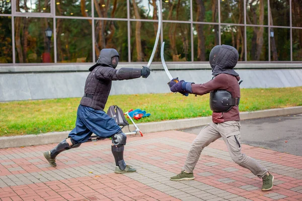 Dos hombres armados lideran una lucha con espadas, una lucha medieval, en un divertido torneo medieval. Competiciones deportivas . —  Fotos de Stock