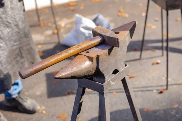 Bir demirci, seyircilerin önünde örsün üzerinde metal dövmesi yapar..