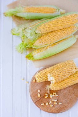 Sofrada tatlı mısırlar var. Kırsal ahşap masadaki koçanlarda taze mısır, yakın plan.