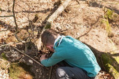 bir çatlak kayanın içindeki bir geocache arayan çocuk