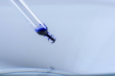 bir pipet ile bir damlacık mavi sıvı