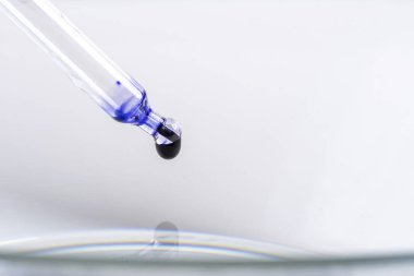bir pipet ile bir damlacık mavi sıvı
