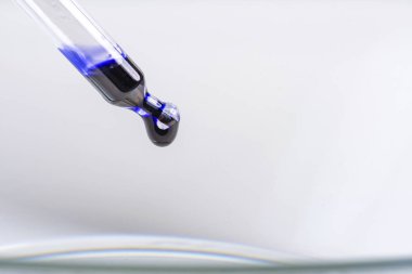 bir pipet ile bir damlacık mavi sıvı